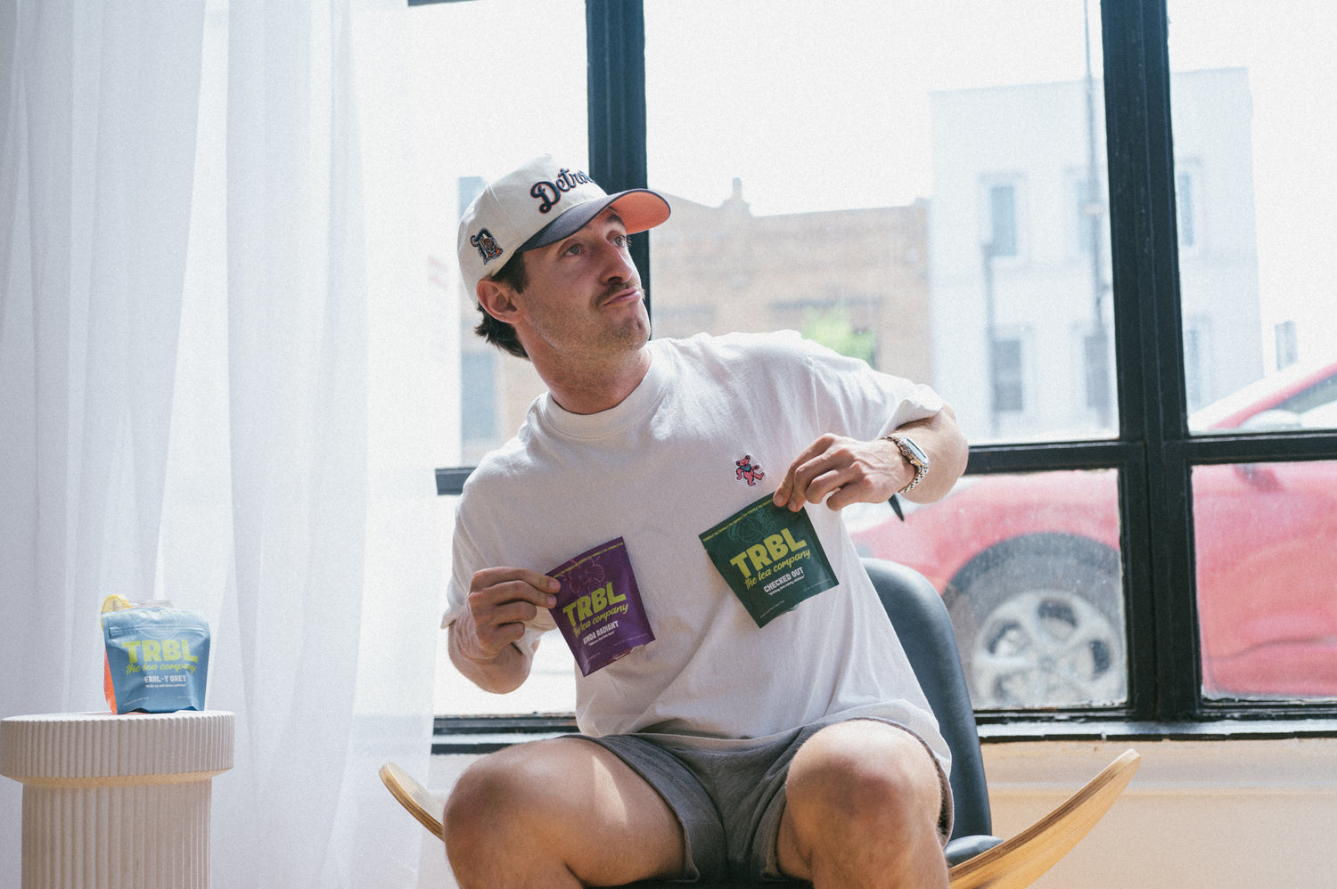 Man holds up TRBL tea and makes a silly face in front of a window