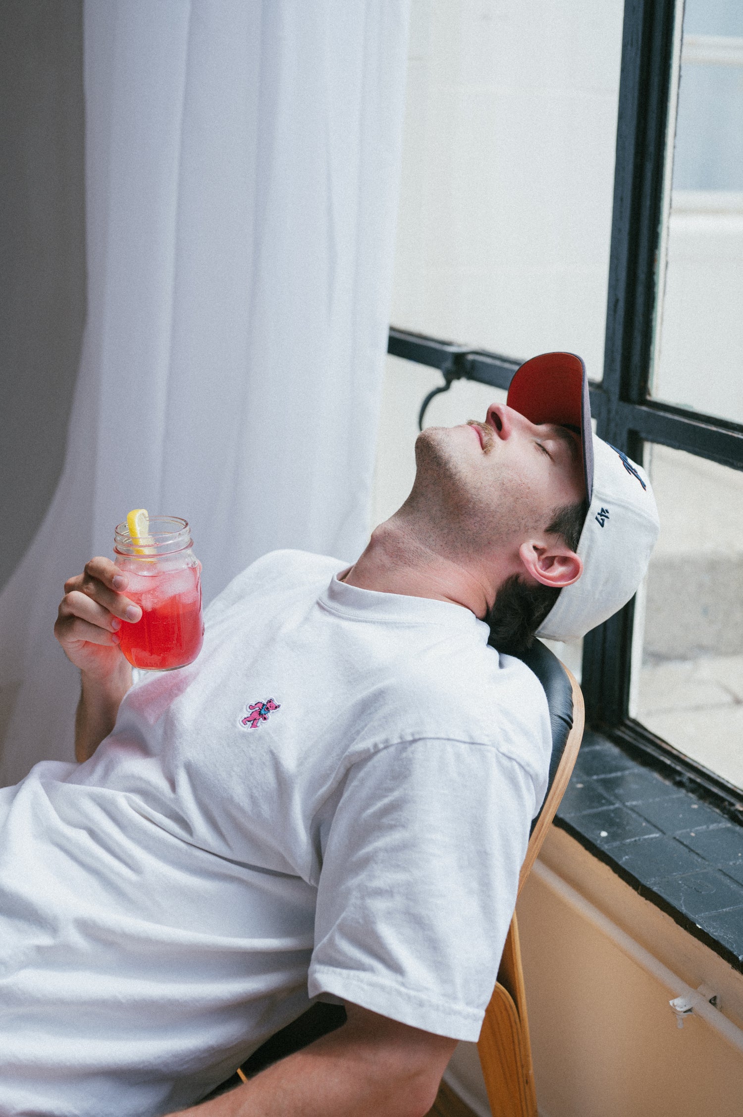 Man drinking herbal tea relaxes in a chair in front of a window